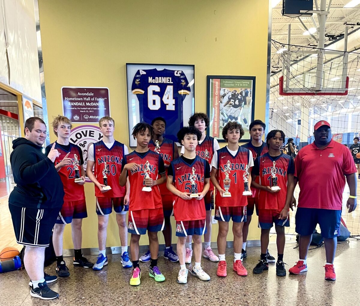 Group of basketball players holding trophies after a tournament.